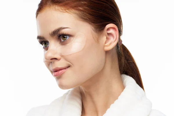 Mulher de roupão branco posando divertidas manchas de cuidados da pele no rosto — Fotografia de Stock