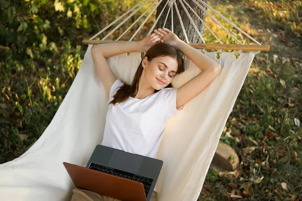 Kadınlar hamakta dizüstü bilgisayarlı tatil internetleriyle yatıyor.