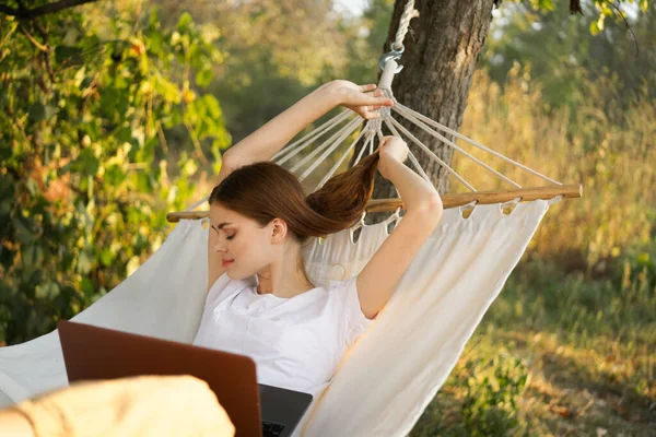 Vrouwen buiten ligt in een hangmat met een laptop freelance internet — Stockfoto