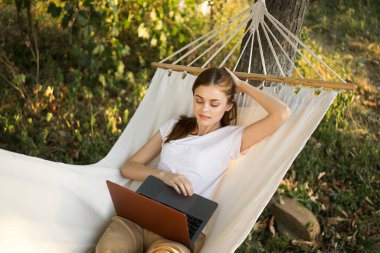 Kadınlar hamakta dizüstü bilgisayarlı tatil internetleriyle yatıyor.