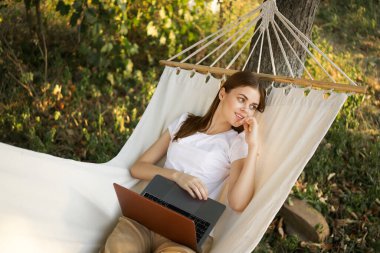 Kadınlar hamakta dizüstü bilgisayarlı tatil internetleriyle yatıyor.