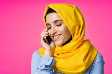 tesettürlü Müslüman kadın telefon iletişim teknolojisi pembe arka plan