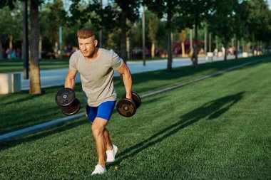 Dambılı erkek sporcu parkı CrossFit egzersizi yapıyor.