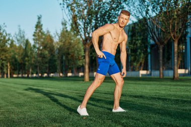 Yaz parkında egzersiz yapan kaslı bir adam.