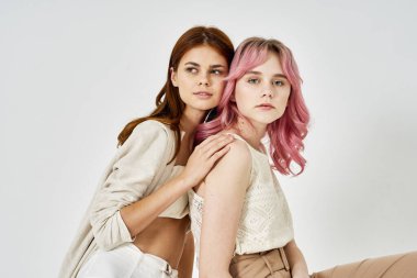 İki kız arkadaş yan yana durmuş, moda zevkini sergiliyorlar.