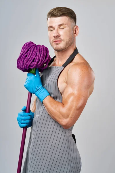 Homem musculado em avental com esfregona posando limpeza — Fotografia de Stock