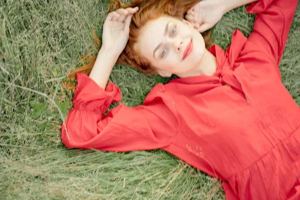 Donna allegra in un abito rosso si trova sull'erba vista dall'alto — Foto Stock