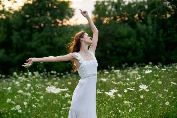Kvinna i vit klänning i ett fält blommor sol natur frihet — Stockfoto
