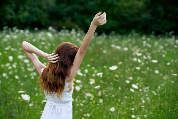 Kvinna i vit klänning i ett fält av blommor gå frihet — Stockfoto