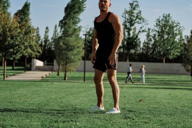 Parktaki çimlerde egzersiz yapan sporcu.