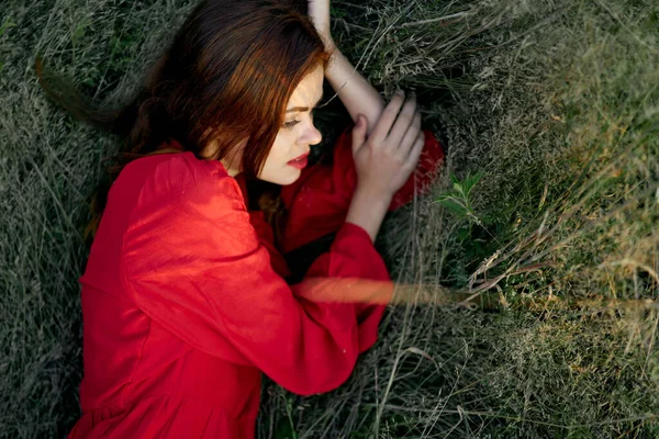Vacker kvinna i röd klänning ligger på gräset poserar ovanifrån — Stockfoto