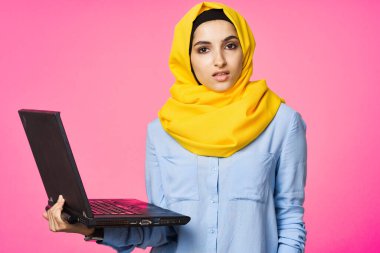 Sarı tesettürlü neşeli Müslüman kadın dizüstü bilgisayar öğreniyor.