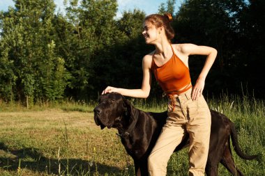 Yazın tarlada köpek dostluğuyla oynayan bir kadın.