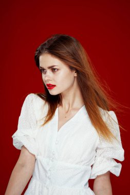 Kırmızı dudaklı neşeli kızıl saçlı kadın. Beyaz elbise. Kırmızı arka plan.