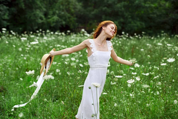Femme en robe blanche chapeau tenant fleurs nature promenade — Photo