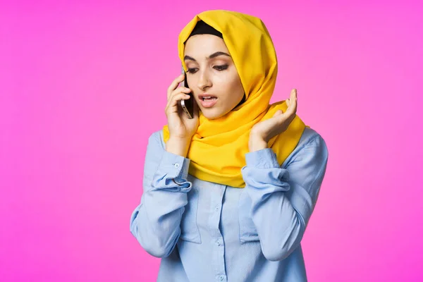 Mujer alegre en un hijab amarillo con un teléfono en sus manos tecnología de comunicación —  Fotos de Stock