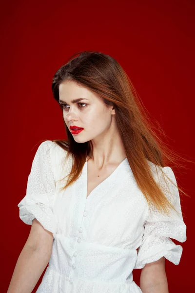 Mulher ruiva alegre com lábios vermelhos vestido branco fundo vermelho — Fotografia de Stock
