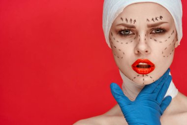 Mavi eldivenli, elinde şırıngayla kırmızı arka planda duran biri.