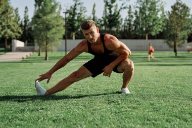 Parktaki çimlerde egzersiz yapan sporcu.