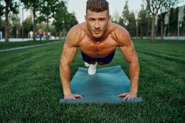 Spor kaslı adam parkta spor yapıyor.