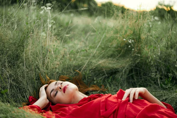 Femme en robe rouge couché sur l'herbe air frais nature romance — Photo