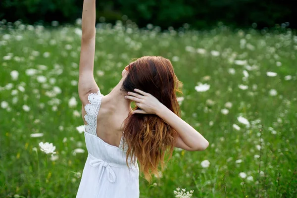 Mulher de vestido branco em um campo de flores caminhar liberdade — Fotografia de Stock