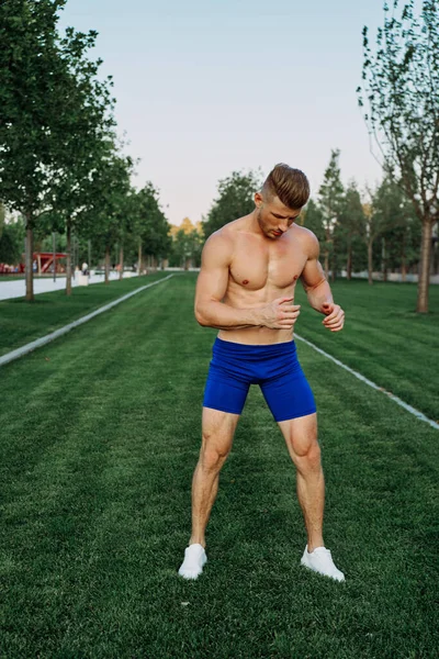 Athletic man with a pumped-up torso exercise in the park fitness — Stock Photo, Image