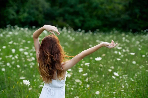 Kvinna i vit klänning i ett fält av blommor gå frihet — Stockfoto