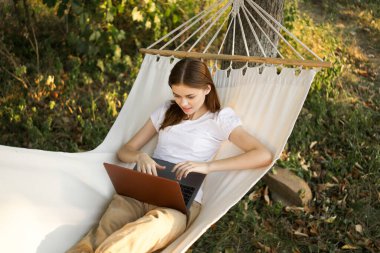 Kadınlar hamakta dizüstü bilgisayarlı tatil internetleriyle yatıyor.