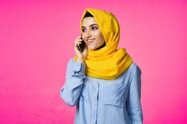 tesettürlü Müslüman kadın telefon iletişim teknolojisi pembe arka plan