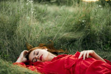 Kırmızı elbiseli kadın çimenlerde uzanıyor taze hava doğa romantizmi