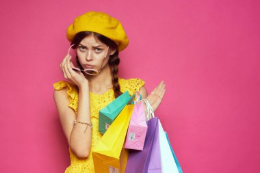 Sarı şapkalı göz kamaştırıcı bir kadın. Alışverişkolik moda tarzı, pembe arka plan.