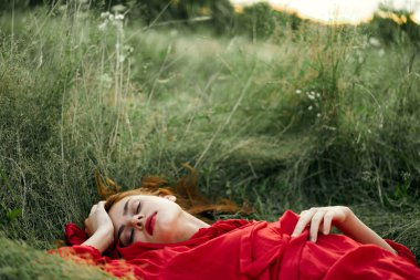 Kırmızı elbiseli kadın çimenlerde uzanıyor taze hava doğa romantizmi