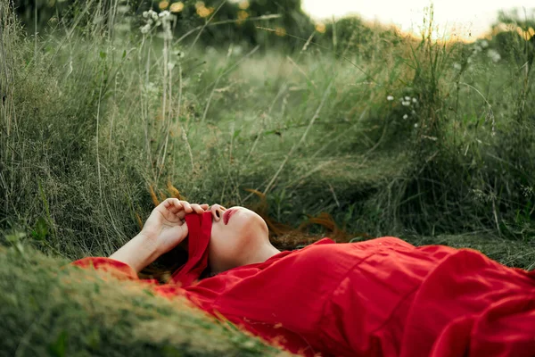 Mujer en vestido rojo acostado en la hierba aire fresco naturaleza romance — Foto de Stock