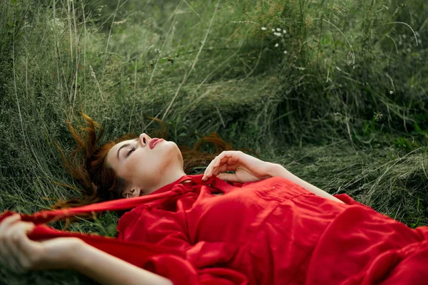 Jolie femme en robe rouge se trouve sur l'herbe dans le champ nature air frais — Photo