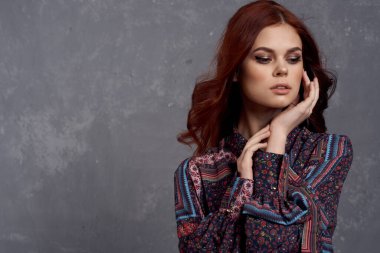 Palto giymiş bir kadın kızıl saç modelini büyülüyor.