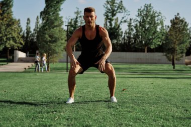 Parktaki çimlerde egzersiz yapan sporcu.