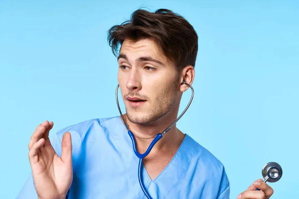 Uomo in uniforme medico trattamento sanitario stetoscopio esame sfondo blu — Foto Stock