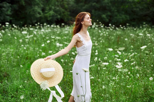 Woman in white dress hat holding flowers nature walk — Stock Photo, Image