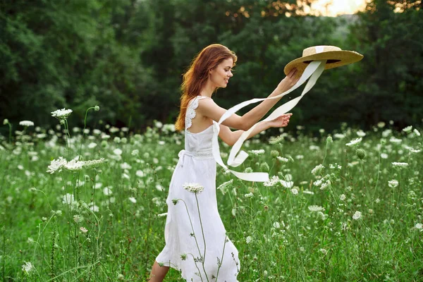 Woman in white dress hat holding flowers nature walk — Stock Photo, Image