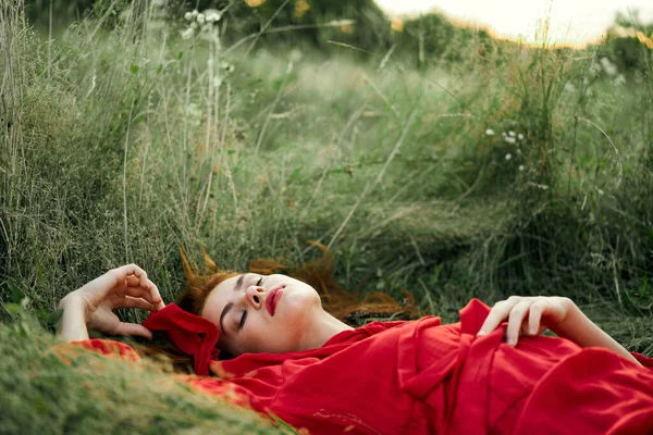 Woman in red dress lying on the grass fresh air nature romance — Stock Photo, Image