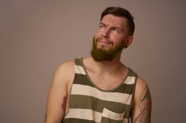 Kollarında çizgili formalı hippi dövmeleri olan ulusal sakallı bir adam.