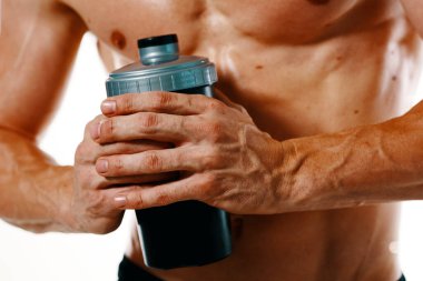 Şişirilmiş gövdesi olan atletik bir adam. Spor tükürüğü şişesi içiyor.