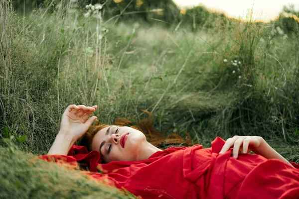 Femme en robe rouge couché sur l'herbe air frais nature romance — Photo