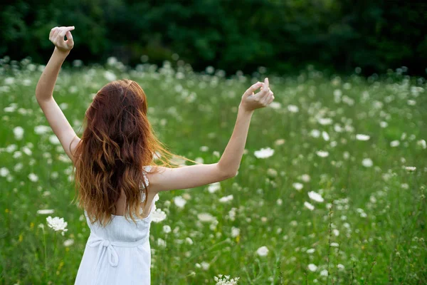 Mulher de vestido branco em um campo de flores caminhar liberdade — Fotografia de Stock