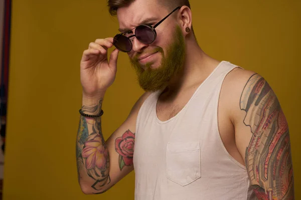 Hombre en una camiseta blanca tatuajes en sus brazos gafas de moda estilo moderno — Foto de Stock