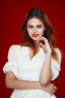 Kırmızı dudaklı neşeli kızıl saçlı kadın. Beyaz elbise. Kırmızı arka plan.