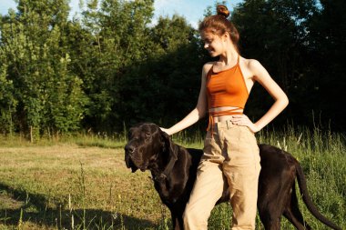 Yazın tarlada köpek dostluğuyla oynayan bir kadın.