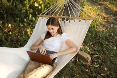 Kadınlar hamakta dizüstü bilgisayarlı tatil internetleriyle yatıyor.