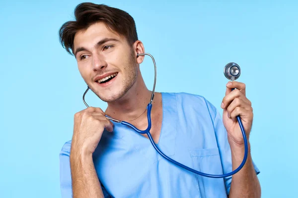 Muž v lékařské uniformě stetoskop vyšetření práce modré pozadí — Stock fotografie